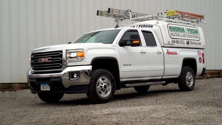 White GMC 2500 HD service truck with ladders on top and Hindman / Person Heating & Air Conditioning branding