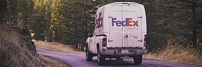 SpaceKap | Home 9 FedEx delivery van driving on a forest road surrounded by tall trees
