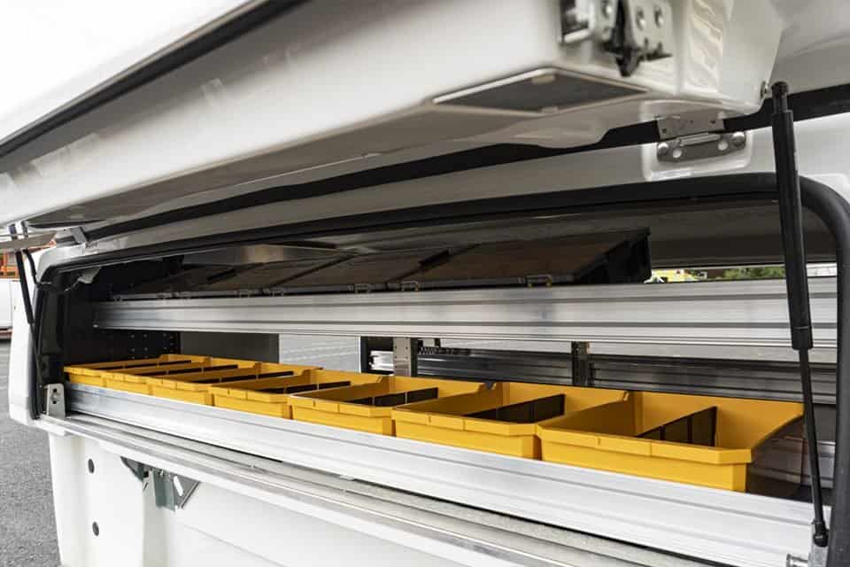 Open side compartment of a white utility van with organized yellow plastic storage bins inside