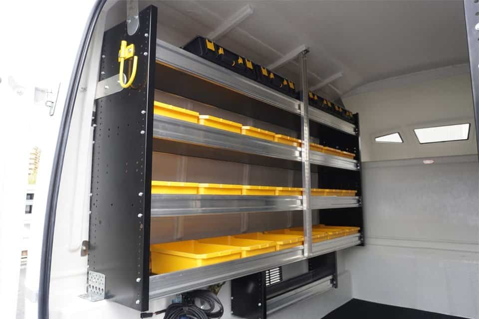 Interior of a van equipped with organized shelving units holding multiple yellow storage bins