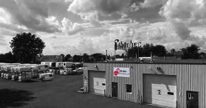 Black and white image of a commercial vehicle service center with multiple trucks and camper vans parked outside