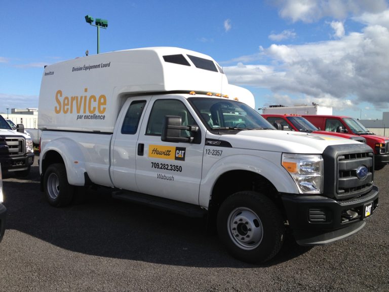 White Ford service truck with Hewitt CAT branding parked in a lot under a blue sky with clouds