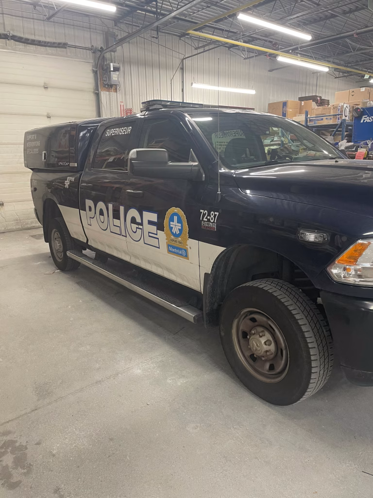 Black and white Montreal police pickup truck labeled Superviseur parked inside a garage