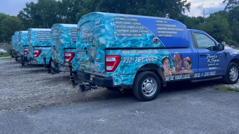 Fleet of Pools & Spas Service, Inc. trucks with blue water-themed wraps parked in a row outdoors