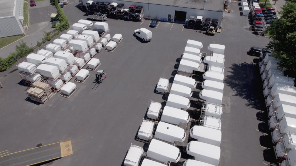 Aerial view of a commercial lot with multiple rows of white truck Spacekap Utility Body and a forklift vehicle