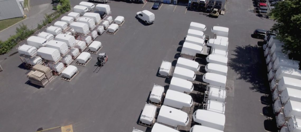 Aerial view of a commercial lot with multiple rows of white truck Spacekap Utility Body and a forklift vehicle