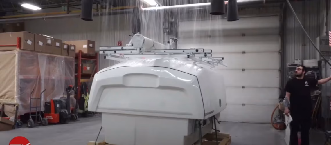 Industrial machine undergoing water flow test inside a warehouse with cardboard boxes and a man observing